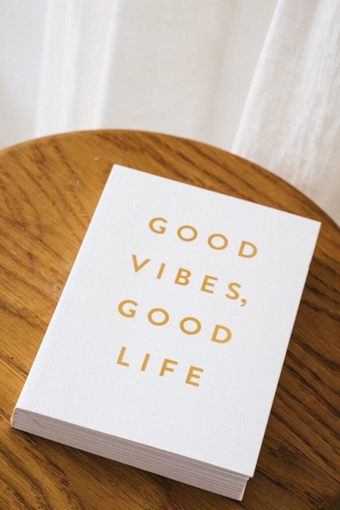 White book titled 'Good Vibes, Good Life' on a wooden table, inspiring message.